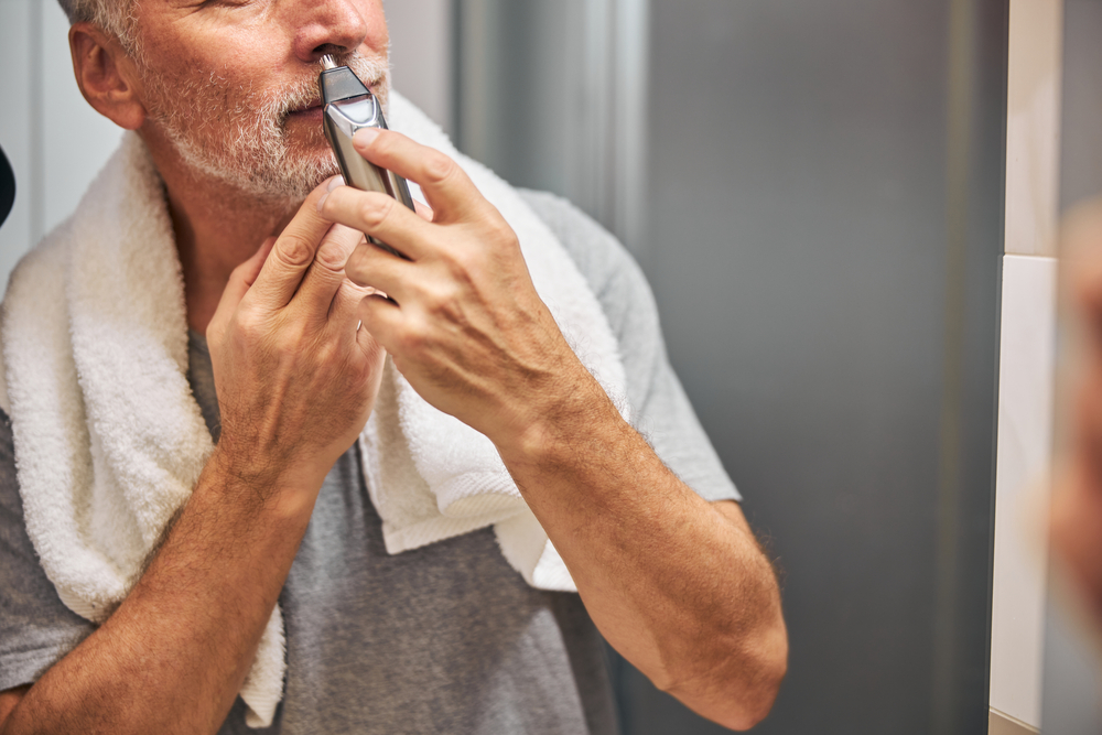 Cropped photo of a tidy senior man tending to his nasal hair with an electric trimmer